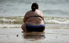Fat woman sitting on beach.webp