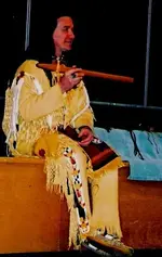 Jess sitting full regalia explaning flute.webp