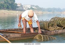 fisherman-in-wooden-boat-checking-his-fishing-pots-made-from-coir-cxdw91.jpg