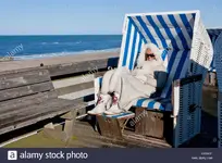 frau-tragt-einen-pelz-mantel-sitzt-in-einem-uberdachten-strandkorb-im-winter-auf-den-nordfrie...webp