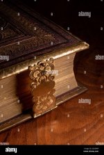 a-leather-bound-antique-book-with-a-decorative-metal-clasp-photographed-on-a-glossy-wooden-sur...jpg