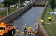 Virginia DOT workers place hose to pump out flood water at thewentrance of Midtown Tunnel pri...webp