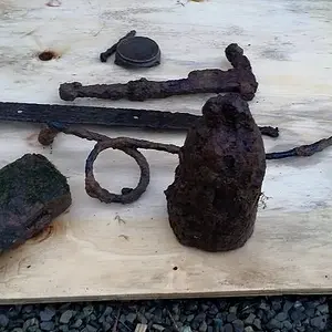 Mason lid with intact porcelain, goat weight (?), a hinge, axe head, random wire, hand tool of some sort.