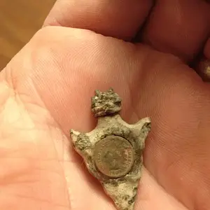 Found this "arrowhead" with an "indianhead penny" embedded in it in an old park.  Penny is about 1/2 size so not real.  Any ideas on what this came fr