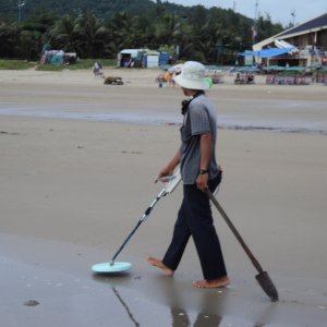Vietnamese guy working the beach.  He drags the shovel behind him to mark where he's been.
