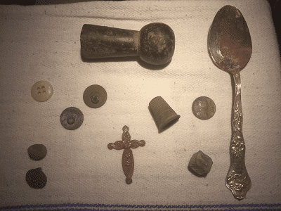 Assorted relics (hames top, thimble, brass cross, flat buttons, musket balls etc).