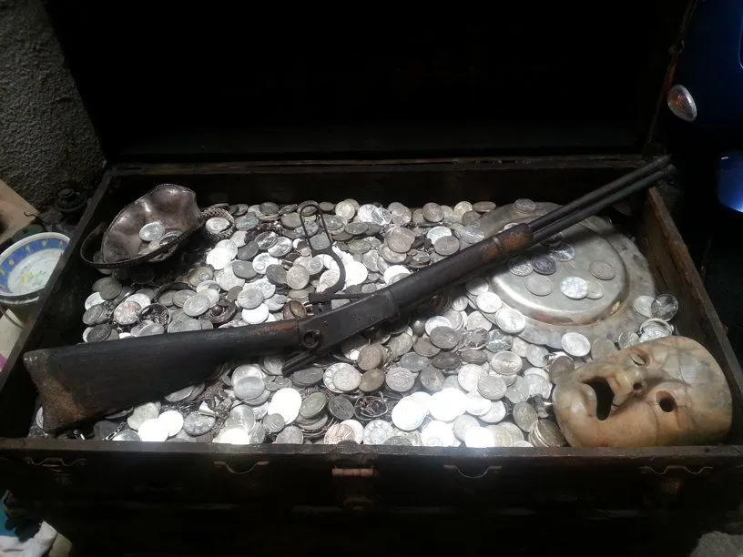 Treasure artifacts like an old riffle, silver plates and a ceramic mask.